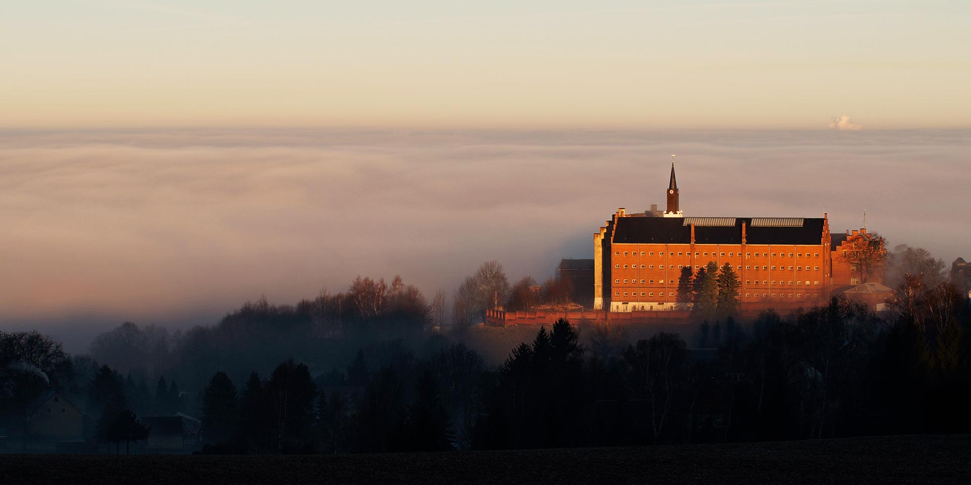 Schloss Hoheneck aus der Ferne mit Landschaft im Nebel